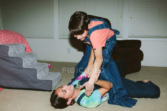 Brother and sister wrestle on the floor of the bedroom — Stock Photo