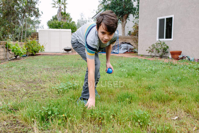Zu Ostern greift ein zehnjähriger Junge mit einem blauen Plastikeier nach einem anderen — Stockfoto