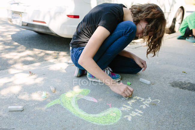No Dia da Terra, uma menina adolescente se baseia em concreto com giz — Fotografia de Stock