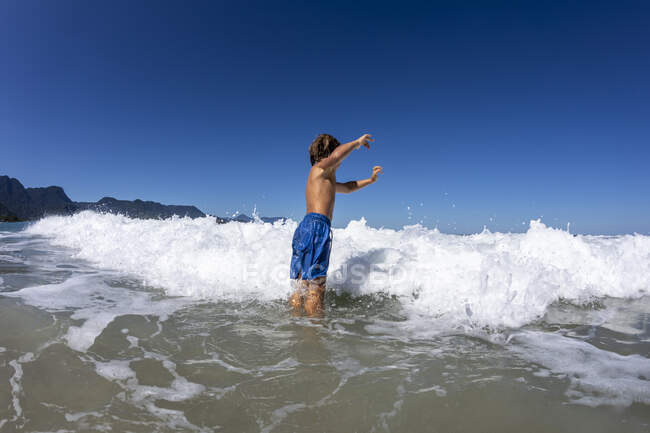 Enfant de 5 ans sautant par-dessus une petite vague — Photo de stock