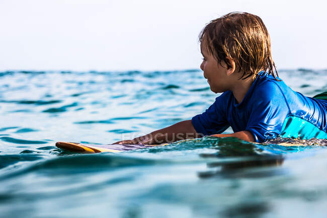 Vista lateral de un surfista de 3 años en tabla de surf de madera - foto de stock