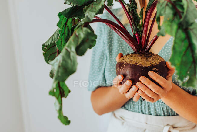 Young woman holding beetroot with green leaves — Stock Photo