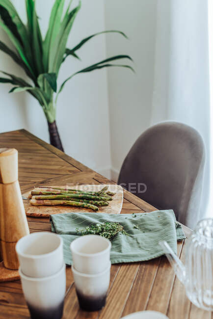 Primer plano de manojo de espárragos en la mesa de madera en la cocina - foto de stock