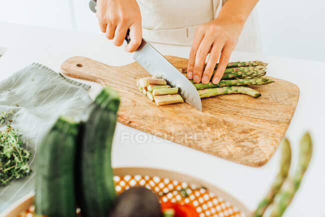Mulher espargos corte em uma tábua de corte à mesa — Fotografia de Stock