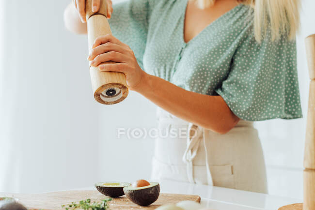 Tiro recortado de mujer preparando aguacate para comer - foto de stock