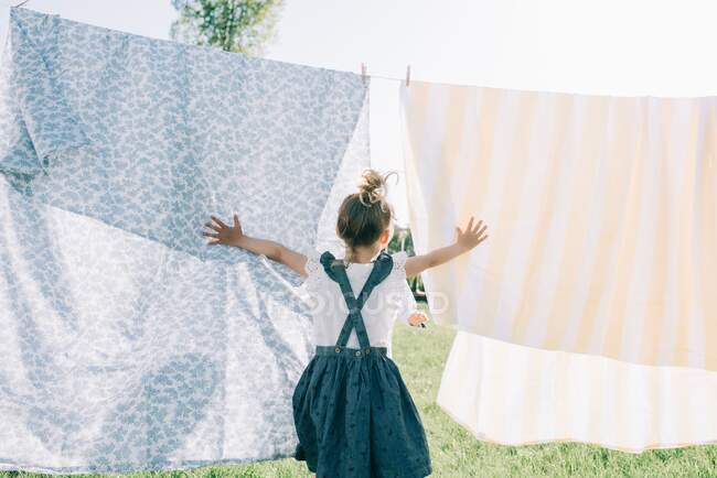 Bonito menina ter diversão com lavanderia ao ar livre — Fotografia de Stock