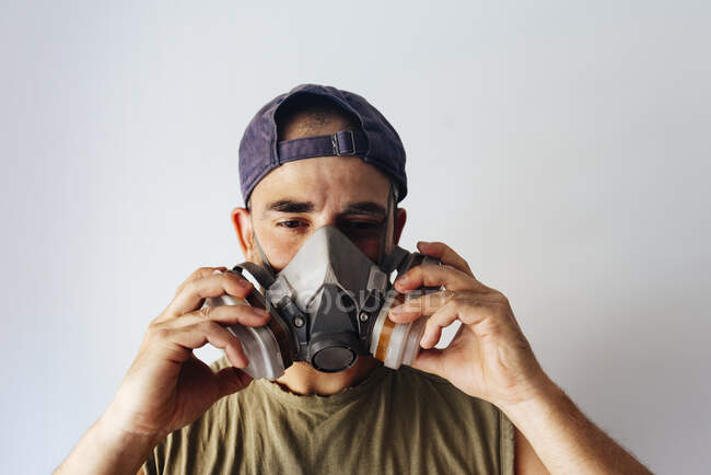 Retrato del pintor de aerógrafos poniéndose su máscara protectora. - foto de stock