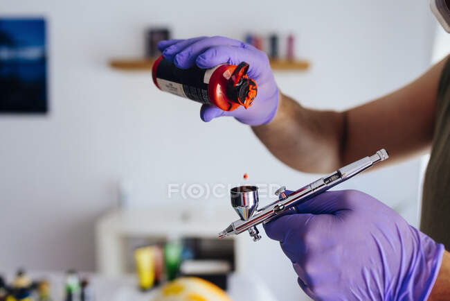 Close up of painter's hands recharging his airbrush. — Stock Photo