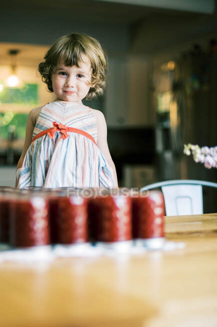 Little silly girl standing on a chair by the homemade plum jam — Stock Photo