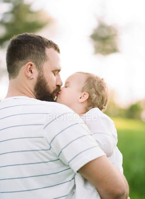 Um retrato de um filme analógico de uma menina de um ano dando um beijo ao pai — Fotografia de Stock