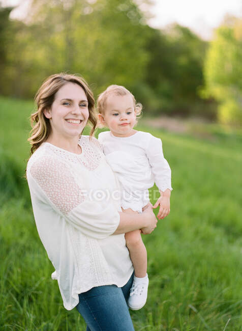 Un retrato de una madre sonriendo felizmente mientras sostiene a su hijo de un año - foto de stock