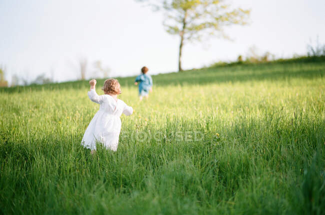 Una fotografía analógica de niñas corriendo hacia un árbol - foto de stock