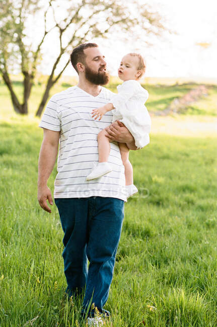 Фотография отца и его дочери в поле, где они целуются на солнце — стоковое фото
