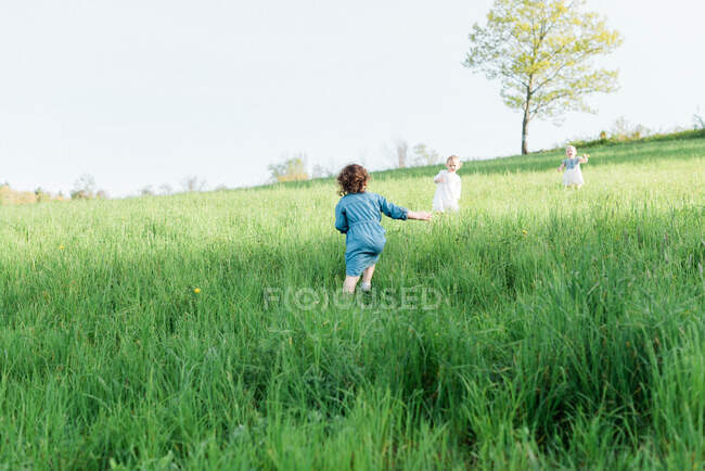 Tres niñas corriendo por un campo - foto de stock