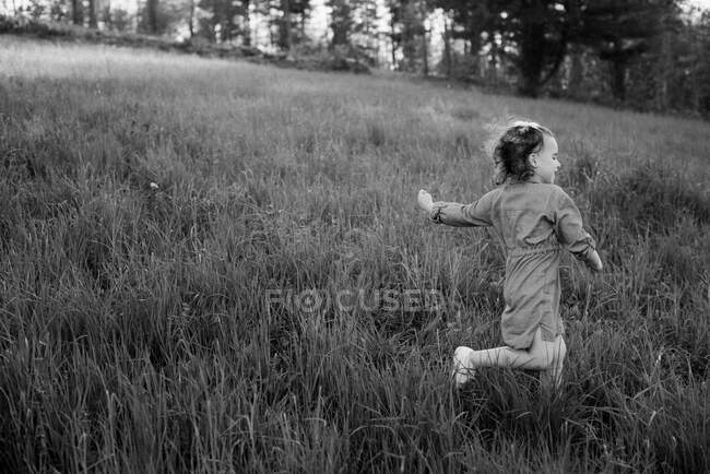 Una chica corriendo rápido por un campo inclinado - foto de stock