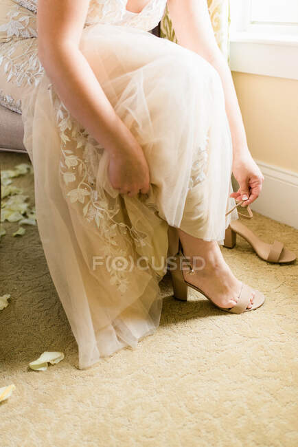 Fotografía de una novia preparándose y poniéndose los talones - foto de stock