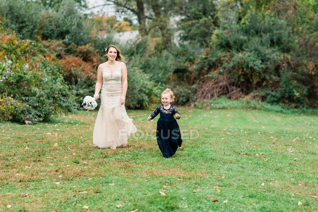 Una sposa che cammina dietro sua figlia e la ragazza dei fiori — Foto stock