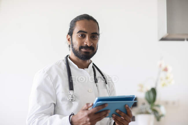 Junger Arzt mit weißem Kittel schaut auf einen Bericht — Stockfoto