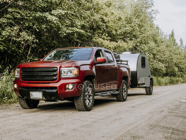 Red pickup truck on dirt road hauling teardrop camper trailer RV — Stock Photo