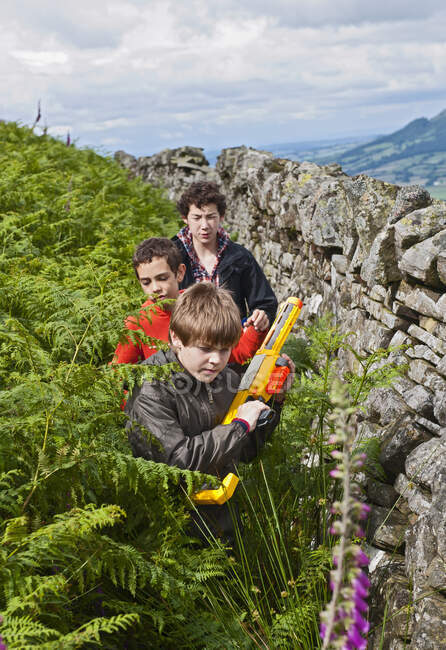 Três adolescentes brincando lá fora com suas armas de brinquedo — Fotografia de Stock