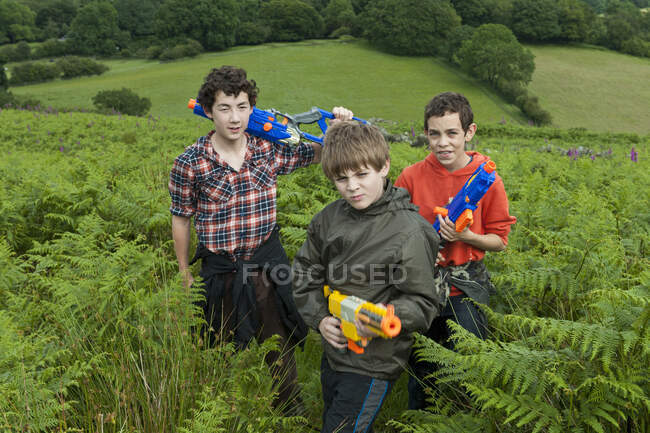 Trois adolescents garçons jouer avec leurs pistolets jouets — Photo de stock