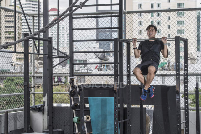 Entrenamiento de hombre en el gimnasio de la azotea en Bangkok - foto de stock