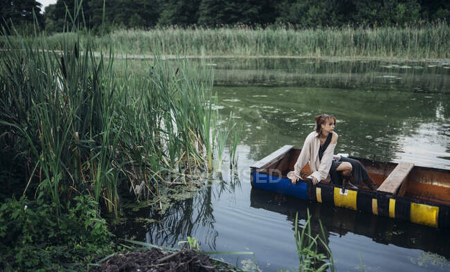 Una mujer en un barco flota en el río - foto de stock