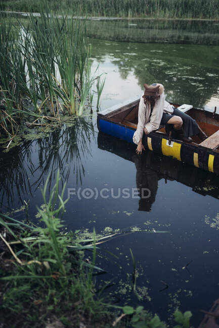 Женщина в лодке тянется к воде — стоковое фото