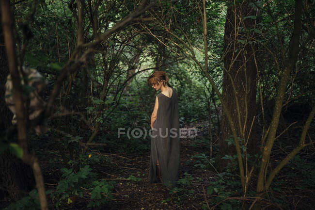 Woman standing back in the forest — Stock Photo