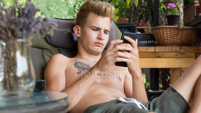 Young man, uses technology on his mobile phone on the terrace at — Stock Photo