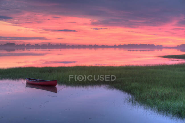 A canoa vermelha flutua no pântano das marés do Maine em meio à luz dramática do amanhecer. — Fotografia de Stock