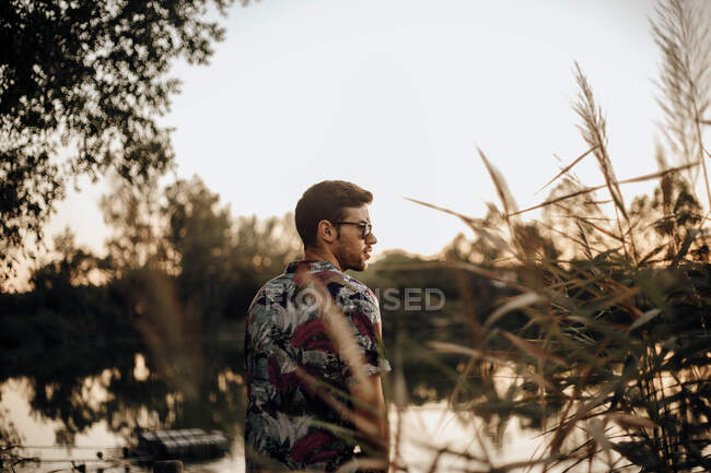 Young man with sunglasses on his back on a lake at sunset — Stock Photo