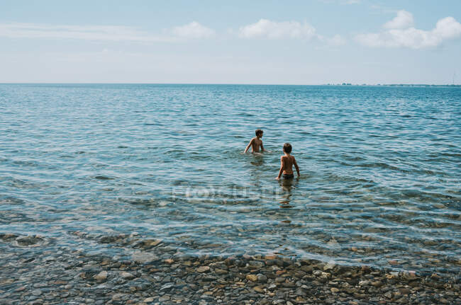 Dos chicos vadeando en el lago Ontario en un día de verano. - foto de stock