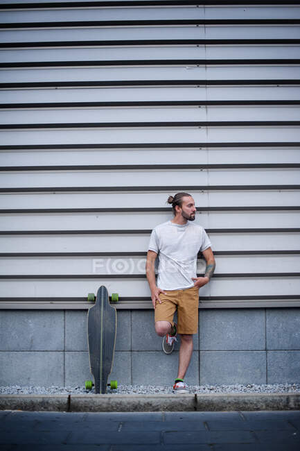 Jeune homme beau avec planche à roulettes en plein air — Photo de stock