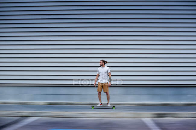 Joven guapo hombre con monopatín al aire libre - foto de stock