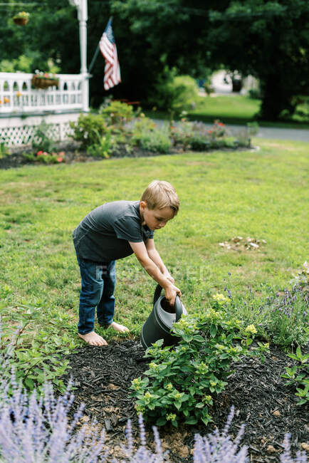 Boy helping with the watering of the plants in the garden — Stock Photo