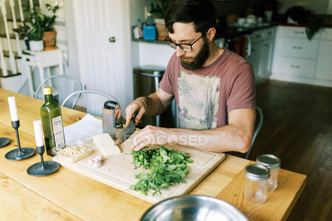 A young man chopping fresh homegrown basil for homemade pesto — Stock Photo