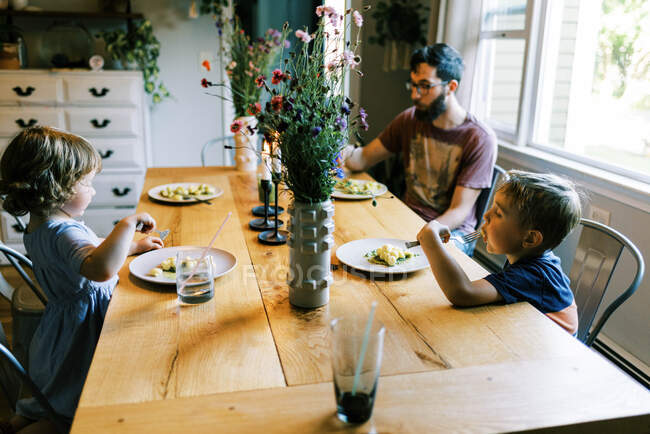 A young family enjoying a dinner together with their homegrown pesto — Stock Photo