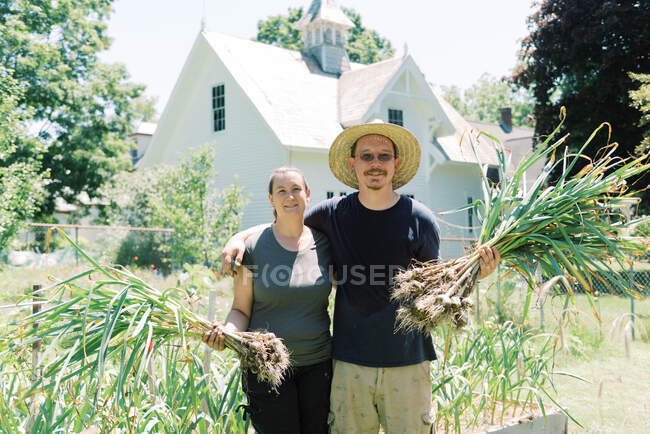Ritratto di una coppia che tiene i bulbi d'aglio appena raccolti — Foto stock