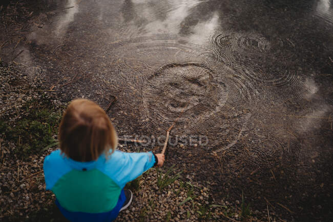 Visão traseira da criança brincando com anéis de água no lago em um parque — Fotografia de Stock