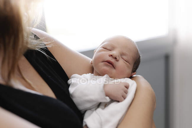 Bambino neonato carino che dorme pacificamente sulle mani della madre a casa — Foto stock