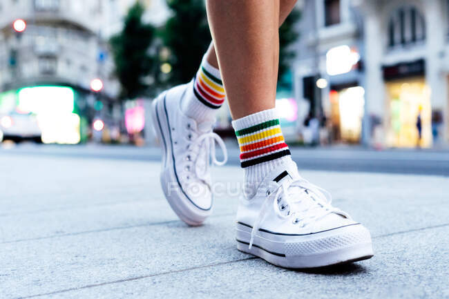 Woman's legs walking down the street with a car in the background — Stock Photo