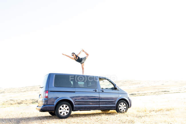 Mulher praticando ioga. pose de dançarina no telhado de uma caravana — Fotografia de Stock
