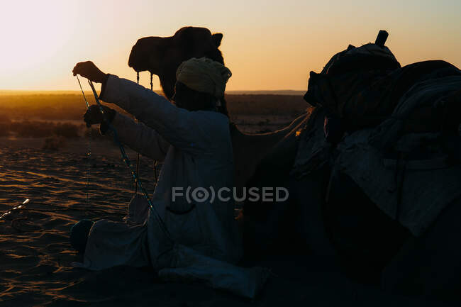 Man with a camel in a desert — Stock Photo