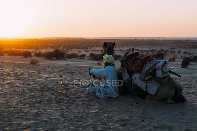 Hombre con camello en el desierto - foto de stock