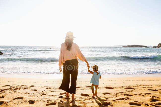 Мати і дитина на заході сонця на пляжі — стокове фото