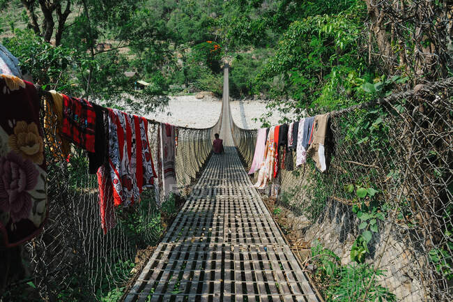 Mann sitzt auf Hängebrücke in Asien — Stockfoto