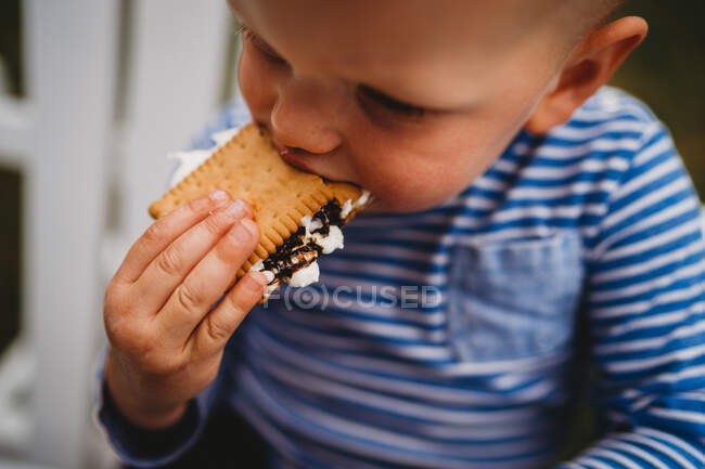 Close up de menino comendo biscoitos e marshmallows smores — Fotografia de Stock