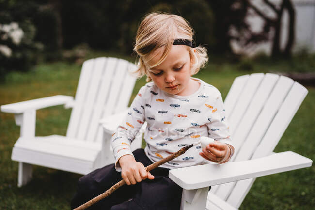 Boy with dirty mouth putting marshmallow on stick to make smores — Stock Photo