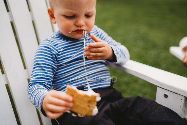 Male toddler eating smores with melted marshmallows — Stock Photo